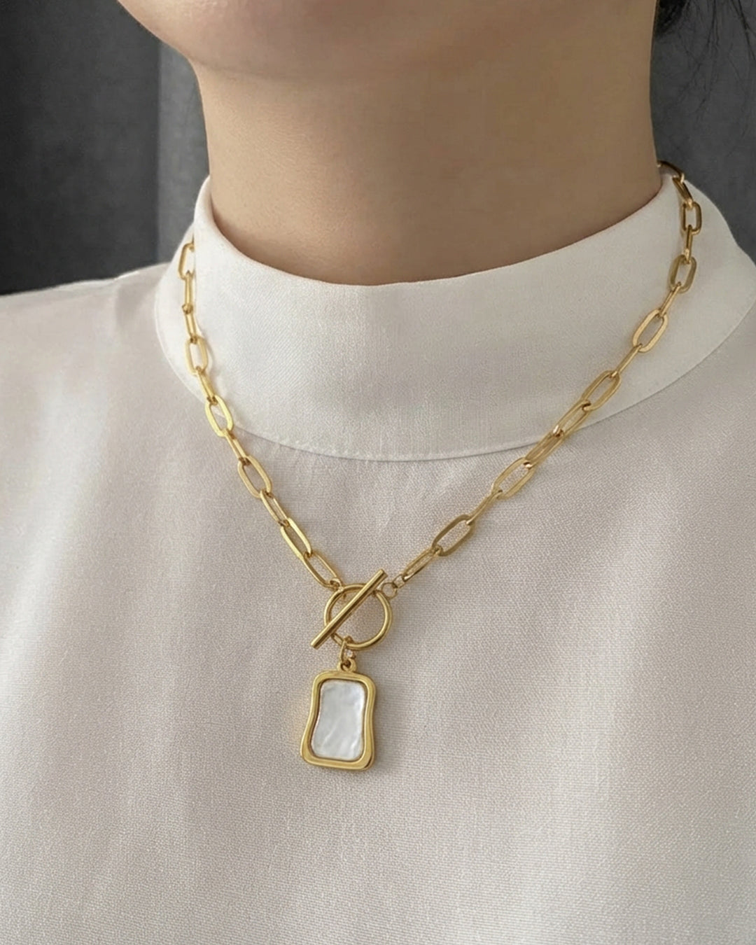 Gold paperclip chain toggle necklace with a mother-of-pearl pendant.