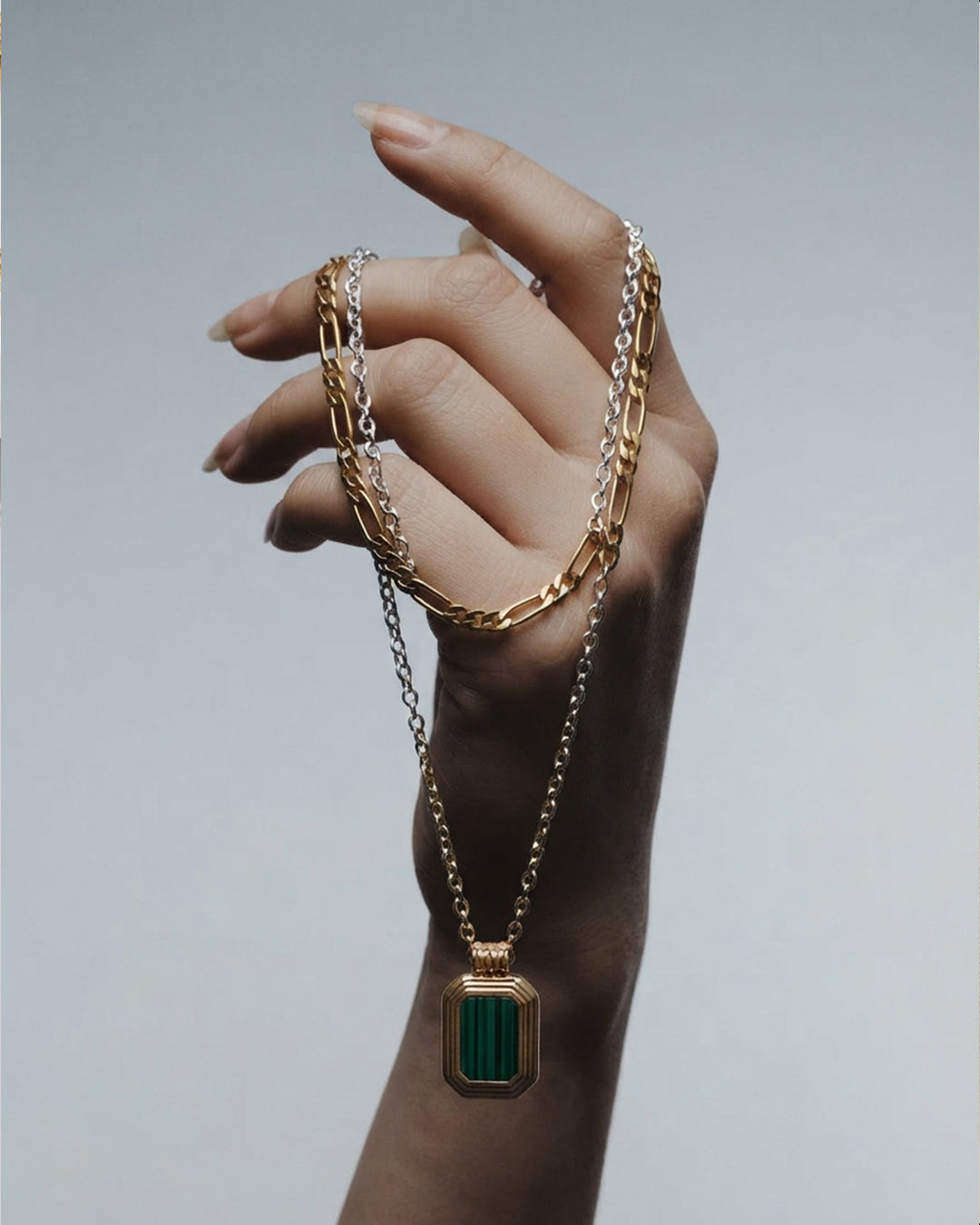 Layered gold chain necklace with a green malachite pendant.